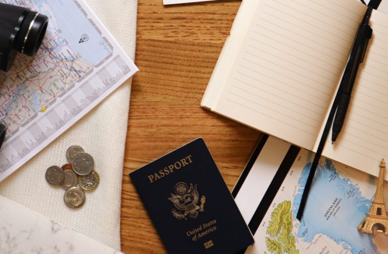 A flat lay featuring my passport, an open journal, a map, and some coins.