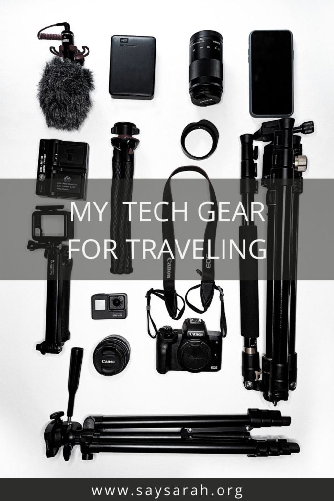 a flat lay of travel tech including cameras, tripods, GoPros, and more