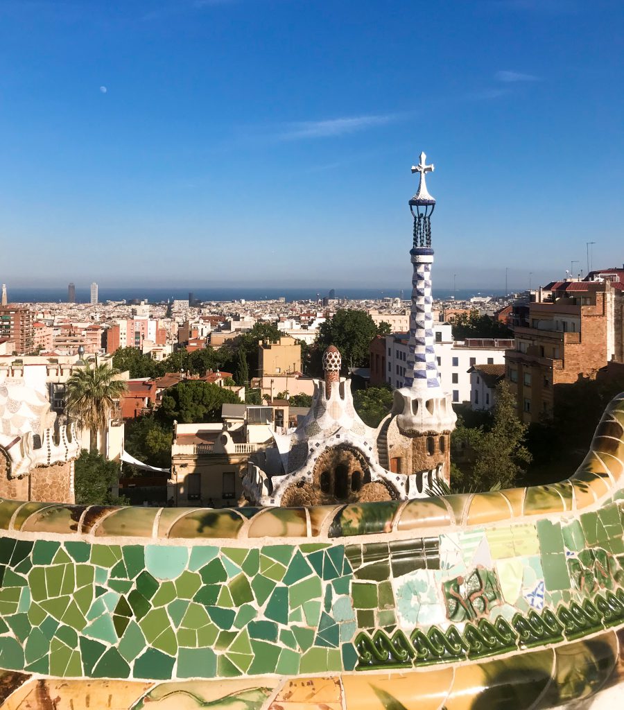 A landscape view form Park Guell of the city of Barcelona, Spain with Gaudi's famous mosaic art in the foreground.