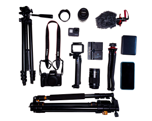 A flat lay of my travel tech gear including CanonM50, tripods, GoPro, iPhone, batteries, lense hood, mic, etc.
