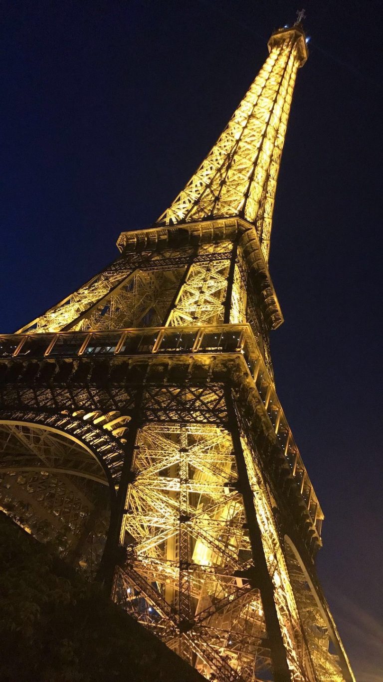Image of the Eiffel Tower lit up at night from a view from the bottom in Paris, France.