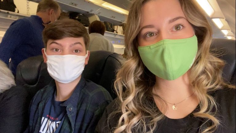 Sarah and her brother on a plane flight wearing their masks during COVID