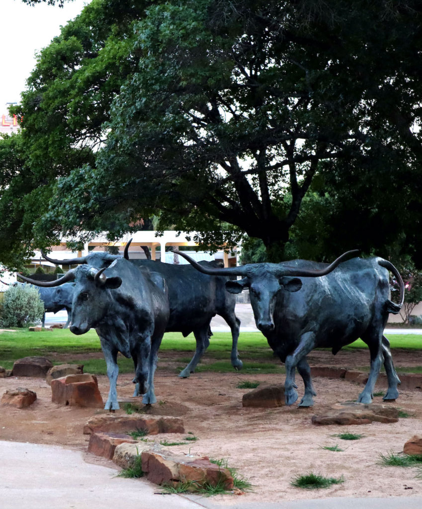 An image of two bull statues at the beginning of the Brazos Suspension Bridge in Waco, Texas.