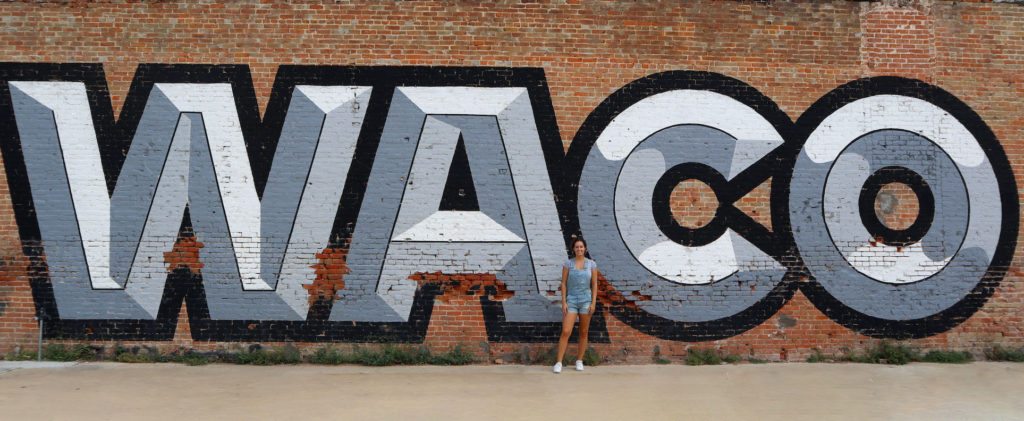 Me, Say Sarah, standing in front of a mural that says WACO in Waco, Texas.