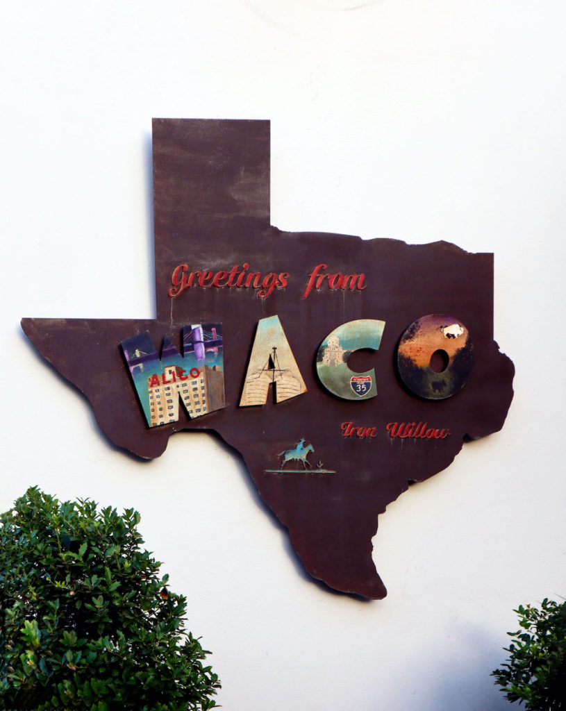 A sign of the state of Texas with the saying "Greeting from Waco".