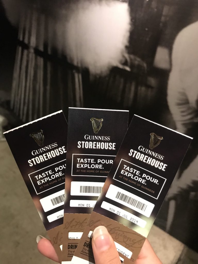 A picture of me holding our entrance tickets to the Guinness Storehouse.
